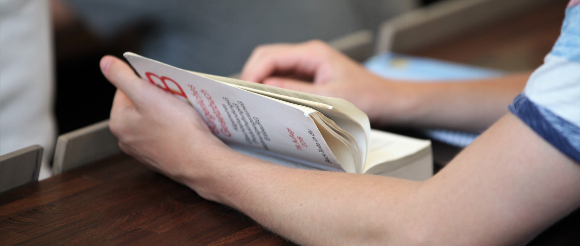 Ein aufgeschlagenes Buch wird gehalten, eine Hand blättert eine Seite um