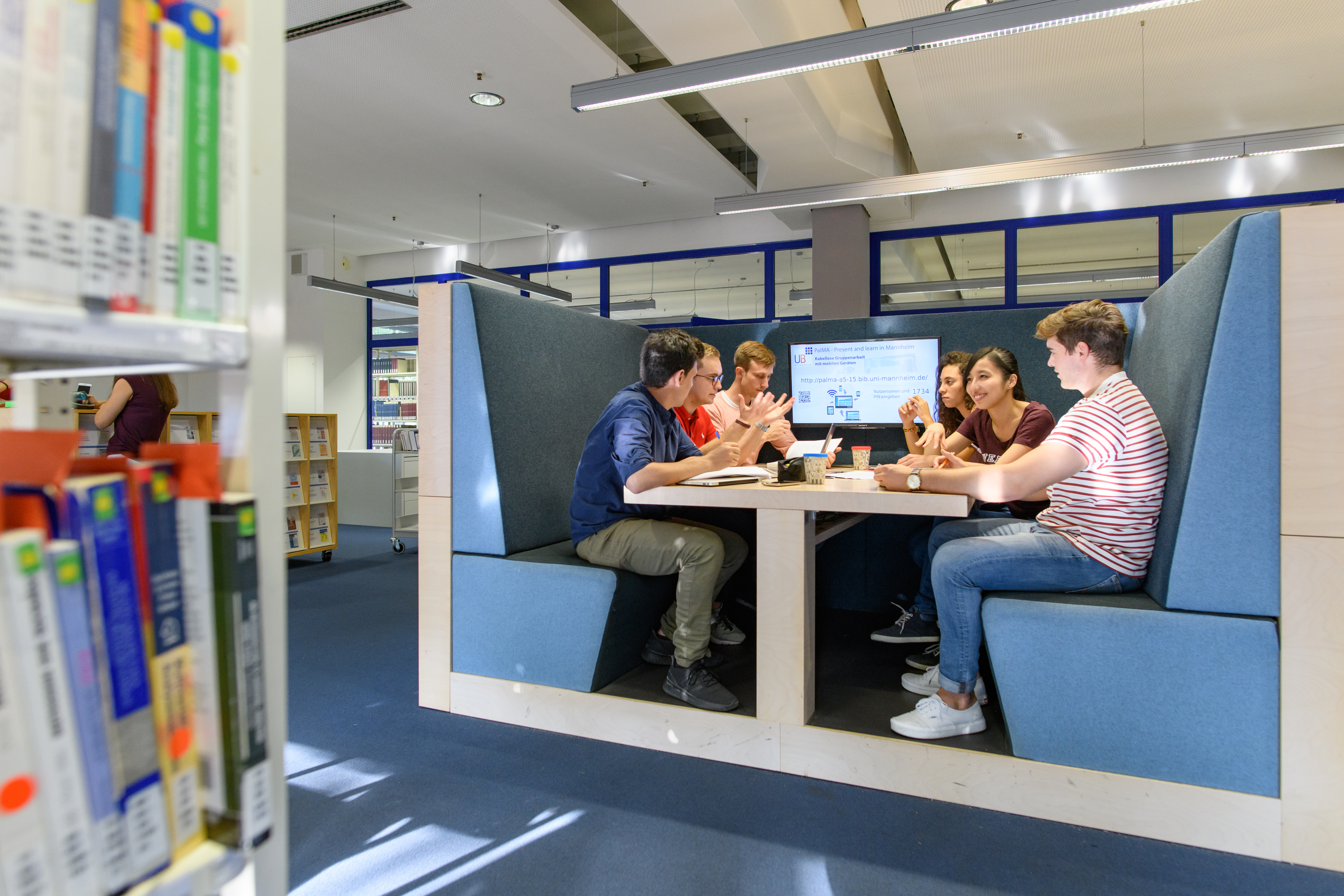 eine Gruppe Studierender sitzt an einem Gruppenarbeitsplatz in der Bibliothek
