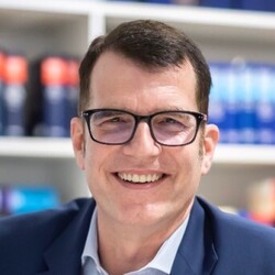 Bernd Zinow in blauem Jacket vor einem Bücherregal