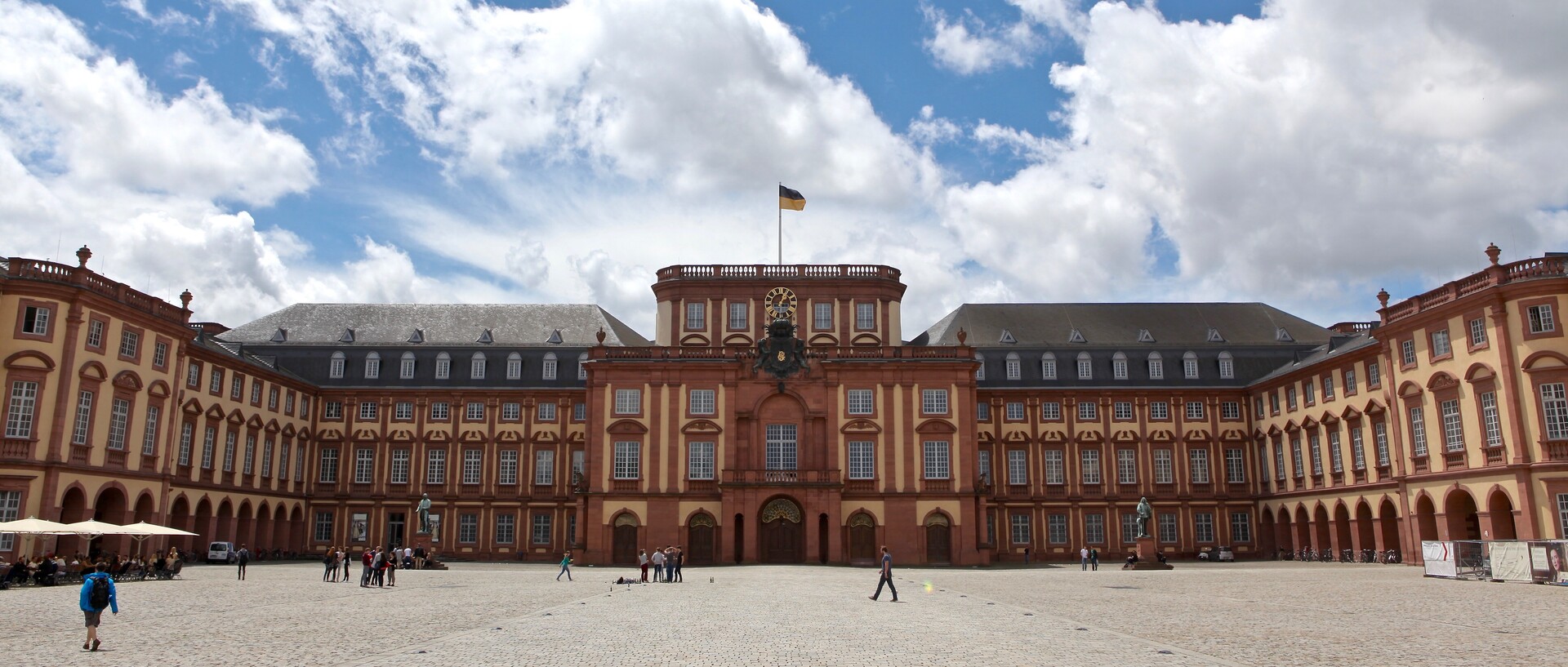 Schloss mit Ehrenhof in der Sonne, blauer Himmel mit weißen Wolken