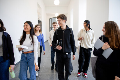 Gruppe Studierender laufen einen Flur im Schloss entlang und unterhalten sich