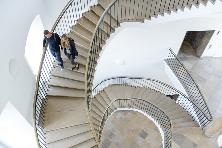 Mann und Frau, die Wendeltreppe im Schloss hinuntergehen