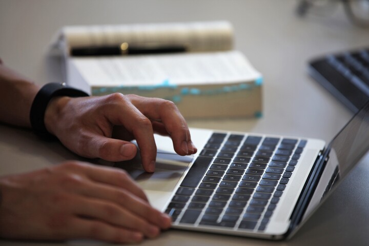 Offener Laptop mit Händen, die an der Tastatur schreiben