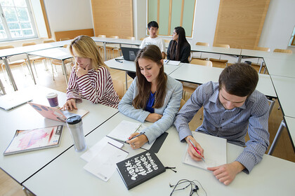 Fünf Studierende sitzen in einem Seminarraum.