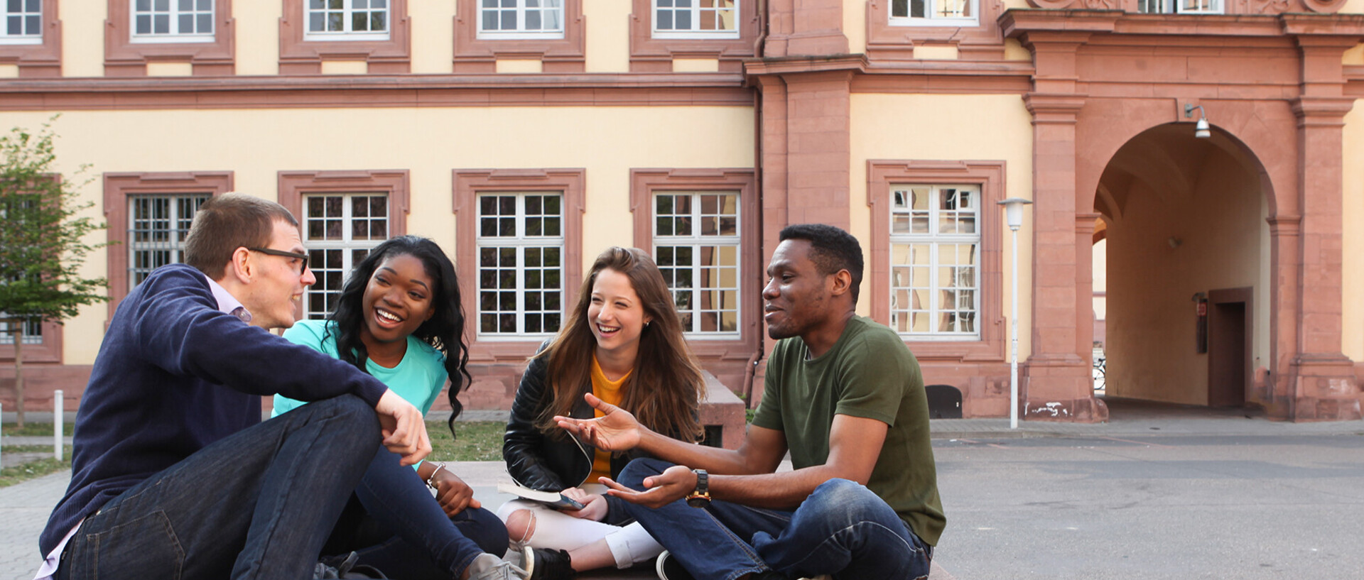 Eine Gruppe Studierender sitzt auf dem Ehrenhof und unterhält sich