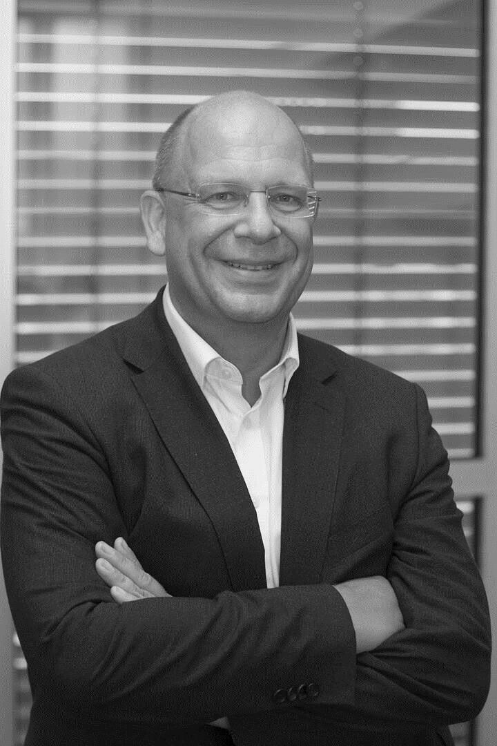 Jörg Risse in suit smiling into camera, arms crossed