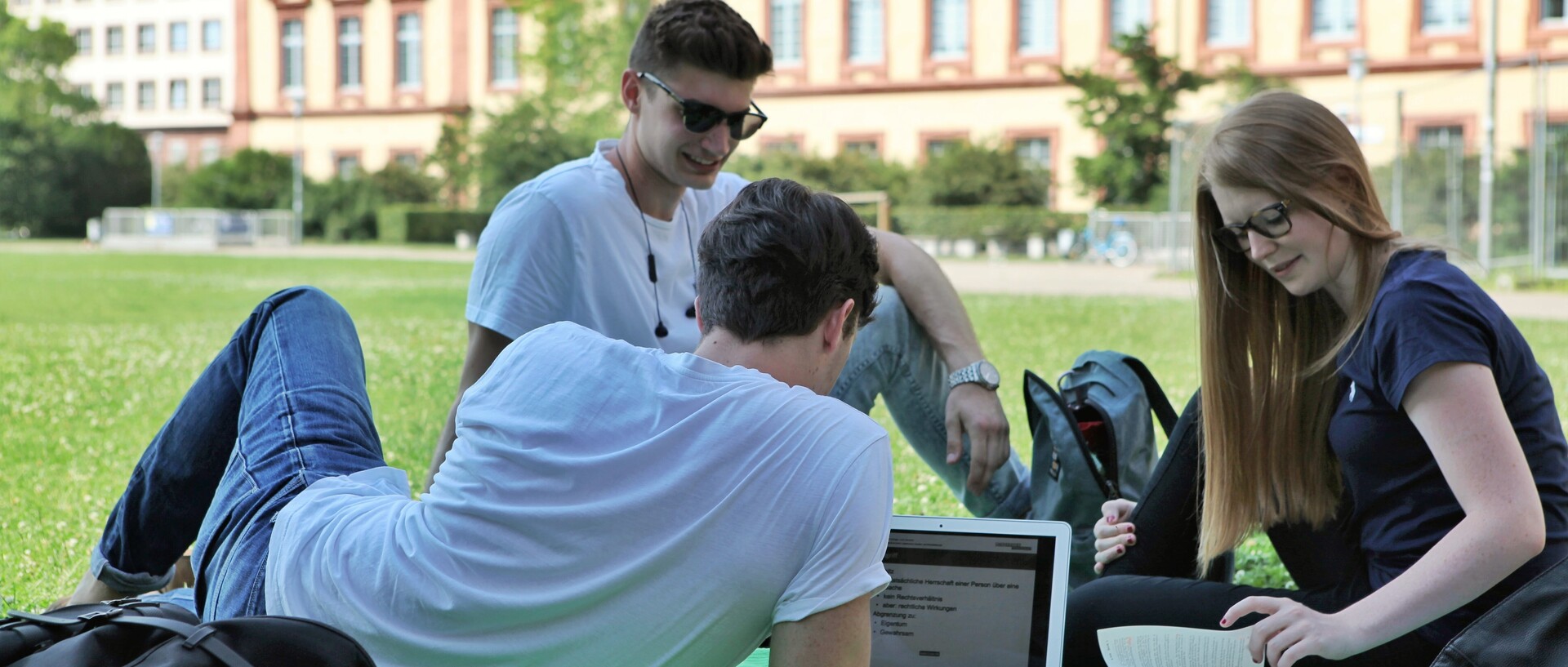 Studierende sitzen auf Mensawiese im Gras