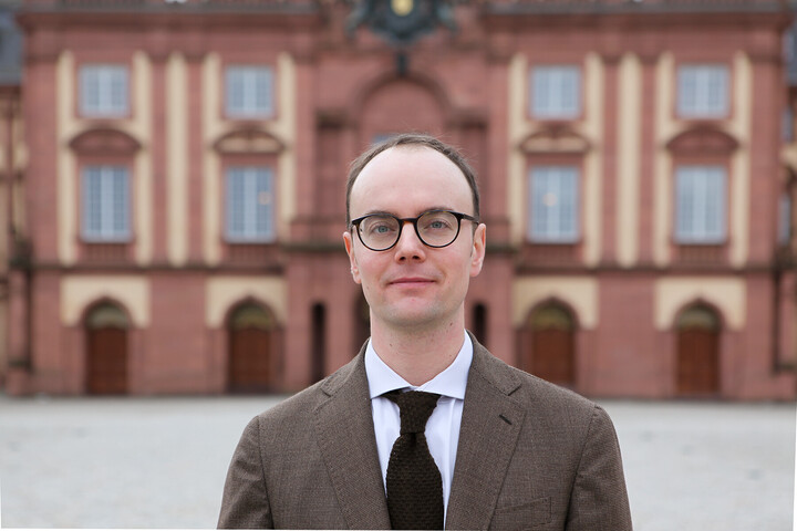 Moritz Renner in Anzug vor dem Schloss