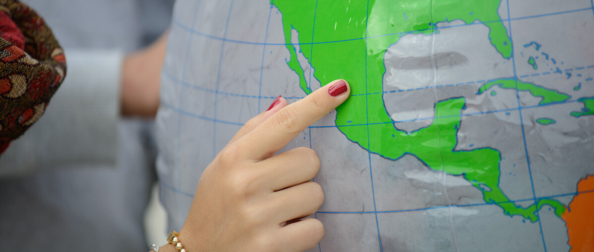Eine Hand zeigt auf einen Ort auf einem Globus