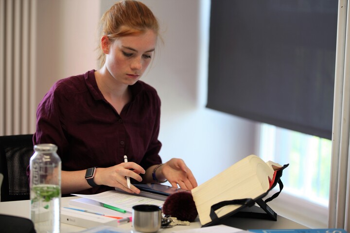 Studentin am Schreibtisch mit aufgeschlagenem Gesetz