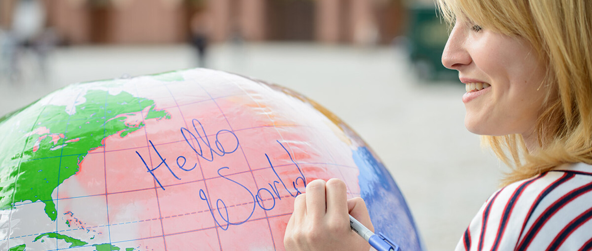 Studentin schreibt die Wrote "hello world" auf einen aufgeblasenen Globus