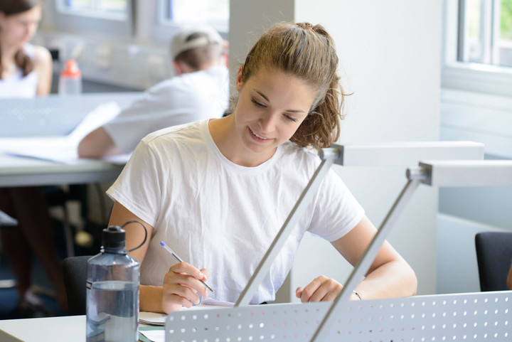 Studentin sitzt in der Bibliothek und lernt