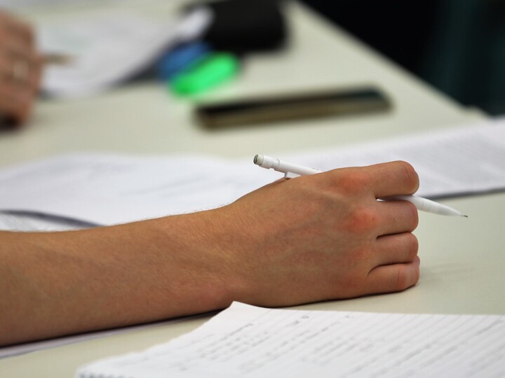 Papier sowie Hand, die einen Stift hält.
