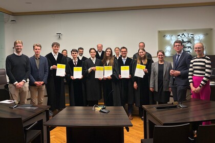 Das MootCourt-Team 2026 steht vor fünf Richtern des VGH. An der Seite des Teams stehen Prof. Stefanie Egidy und Prof. Dr. Michael Müller sowie die Coaches Tim Gromes, Moritz Kurth und Alena Lennartz.