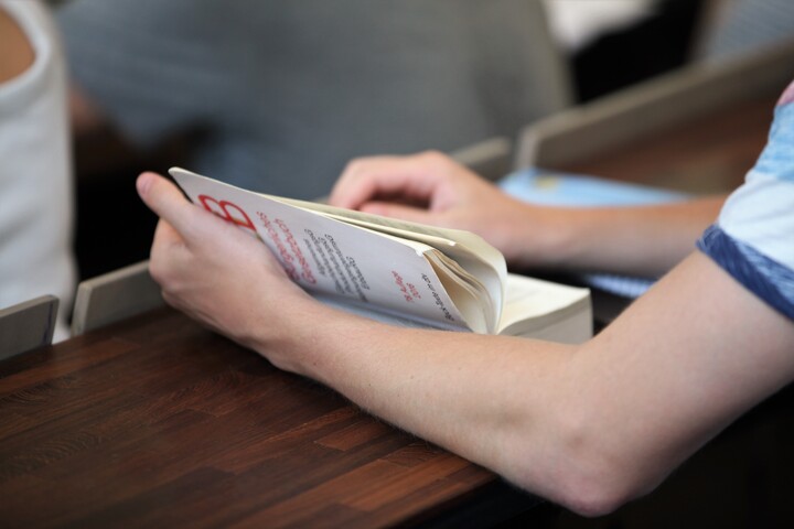 Aufgeschlagenes Buch, eine Hand blättert eine Seite um