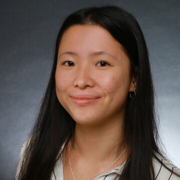 Portrait von Lily Yu. Sie trägt ein weißes Hemd mit Streifen und steht vor einem grauen Hintergrund.