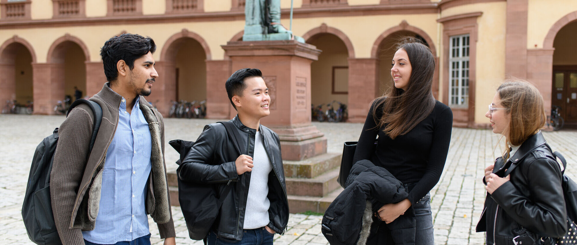 Das Bild zeigt vier Leute auf dem Ehrenhof der Universität Mannheim