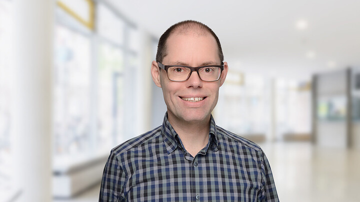 Martin Peitz in Hemd vor einem großen Raum