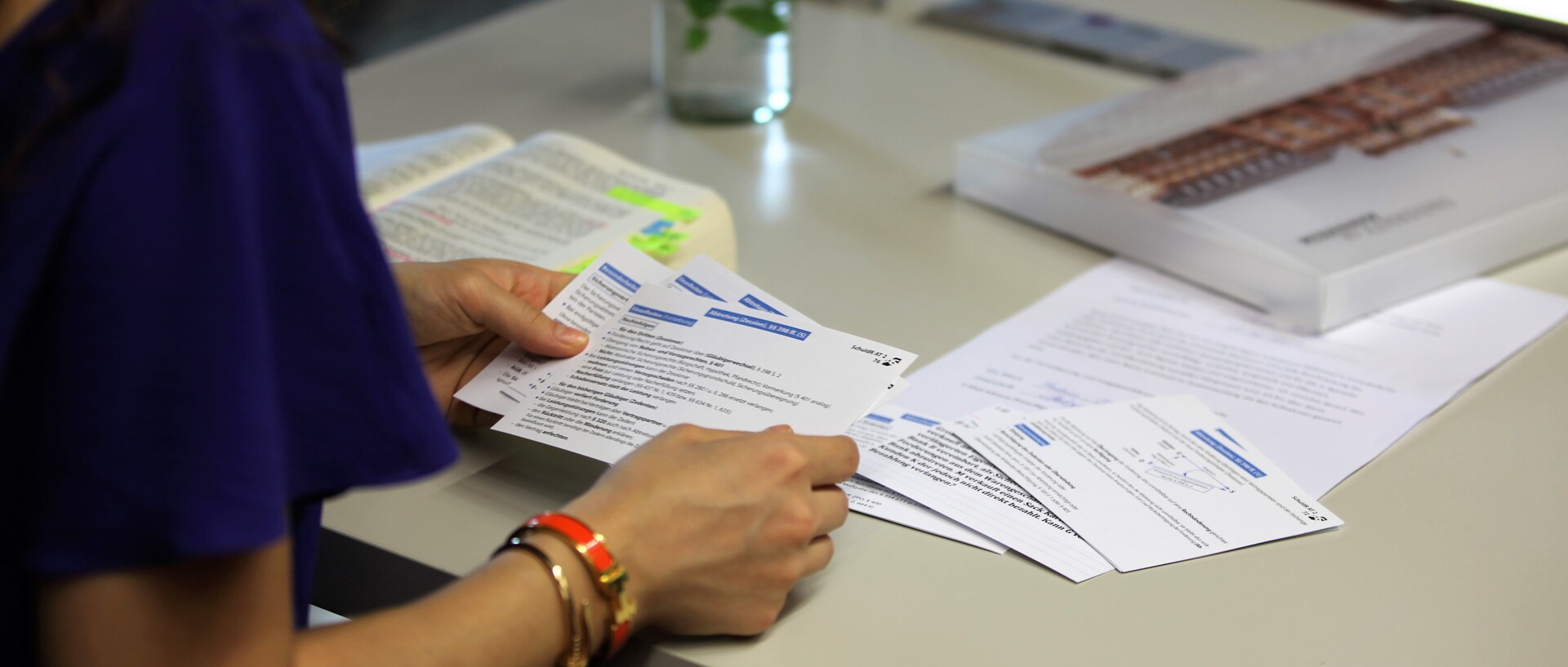 Studentin lernt mit Buch und Karteikarten