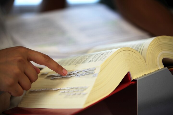 Aufgeschlagenes Buch mit Hand, die auf etwas zeigt