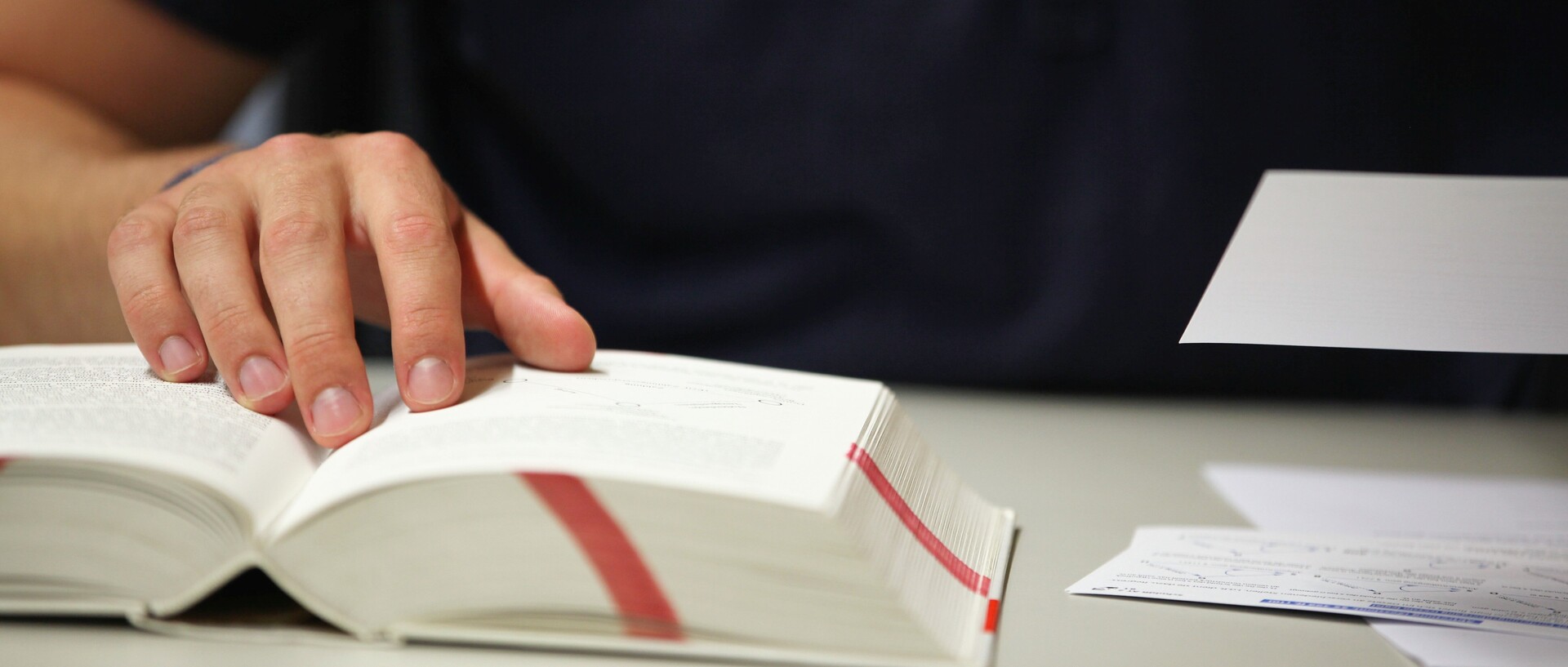 Buch mit Markierungen und einer Hand, die auf etwas zeigt