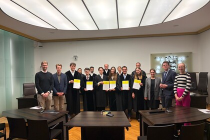 Eine Gruppe der Teilnehmenden am Moot Court zeigt lächelt in die Kamera und zeigt die Urkunden