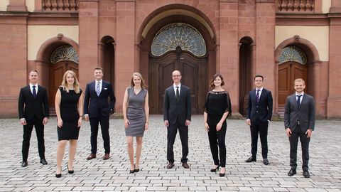 Gruppe von Studierender in formeller Kleidung vor dem Schloss