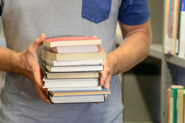 Zwei Hände halten viele Bücher fest
