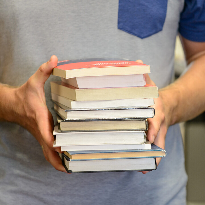 Zwei Hände halten viele Bücher fest