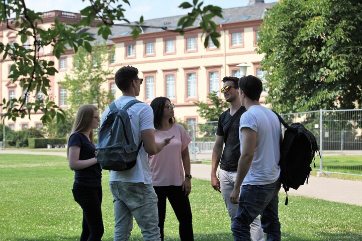 Eine Gruppe Studierender steht auf der Mensawiese und unterhält sich