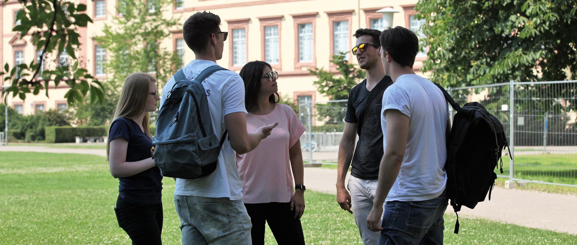 Studierende stehen auf der Mensawiese und unterhalten sich