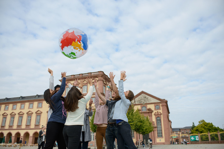 Eine Gruppe Studierender wirft einen aufgeblasenen Globus in die Luft