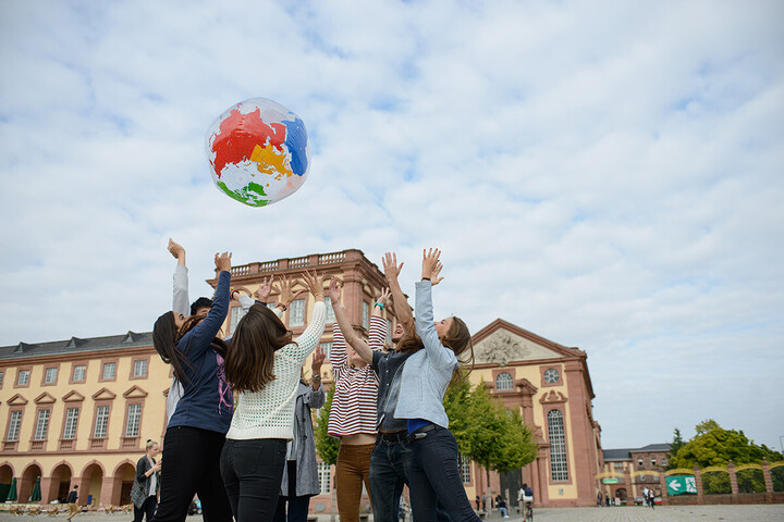 Studierende vor dem Schloss werfen aufgeblasenen Globus in die Luft