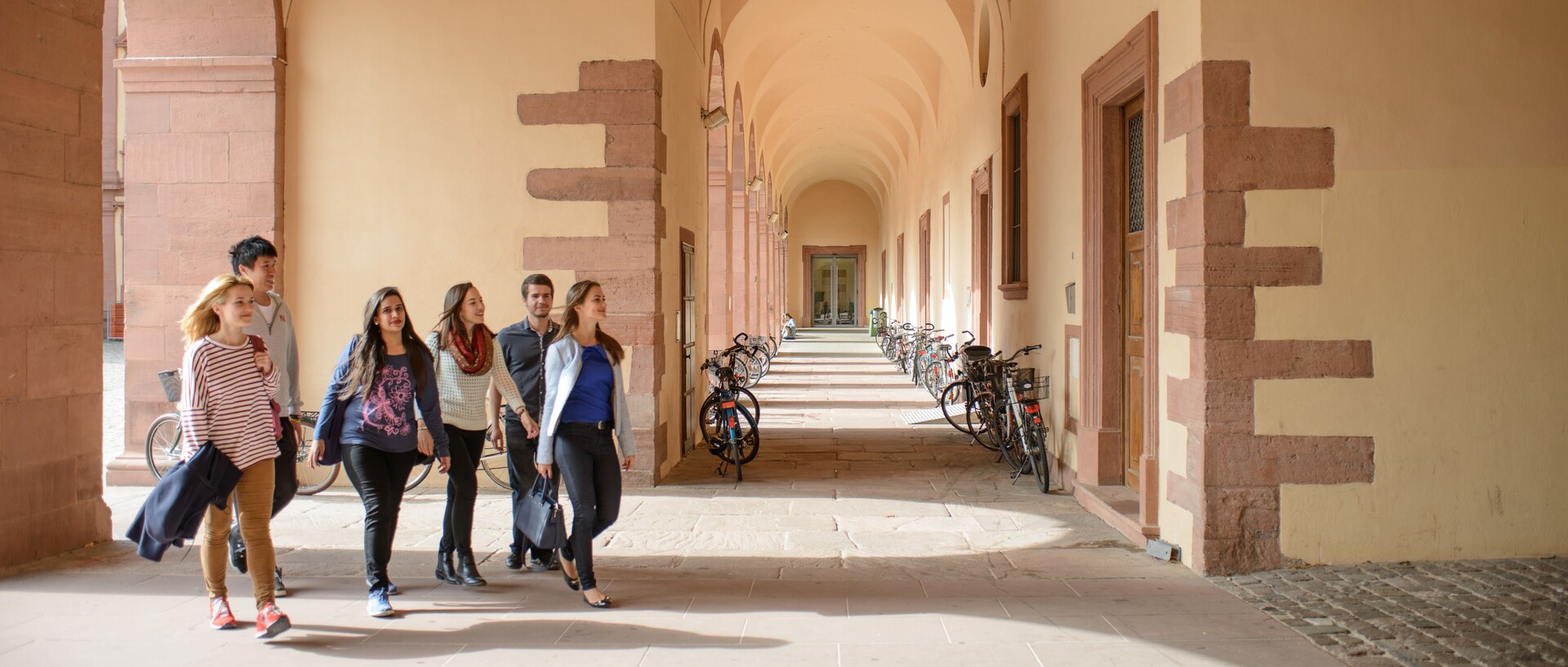 Studierende laufen durch die Arkaden des Schlosses