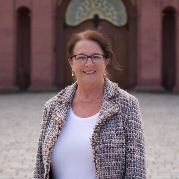 Ute Arns. Sie trägt ein weißes Oberteil sowie eine bunte Jacke.
