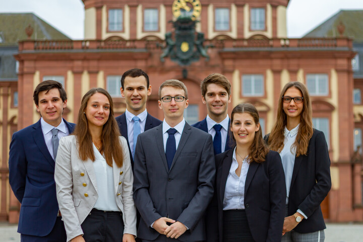 Gruppe von Studierender in formeller Kleidung vor dem Schloss