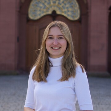 Wissenschaftliche Mitarbeiterin Laura Prisen. Sie trägt einen weißen Rollkragenpullover.