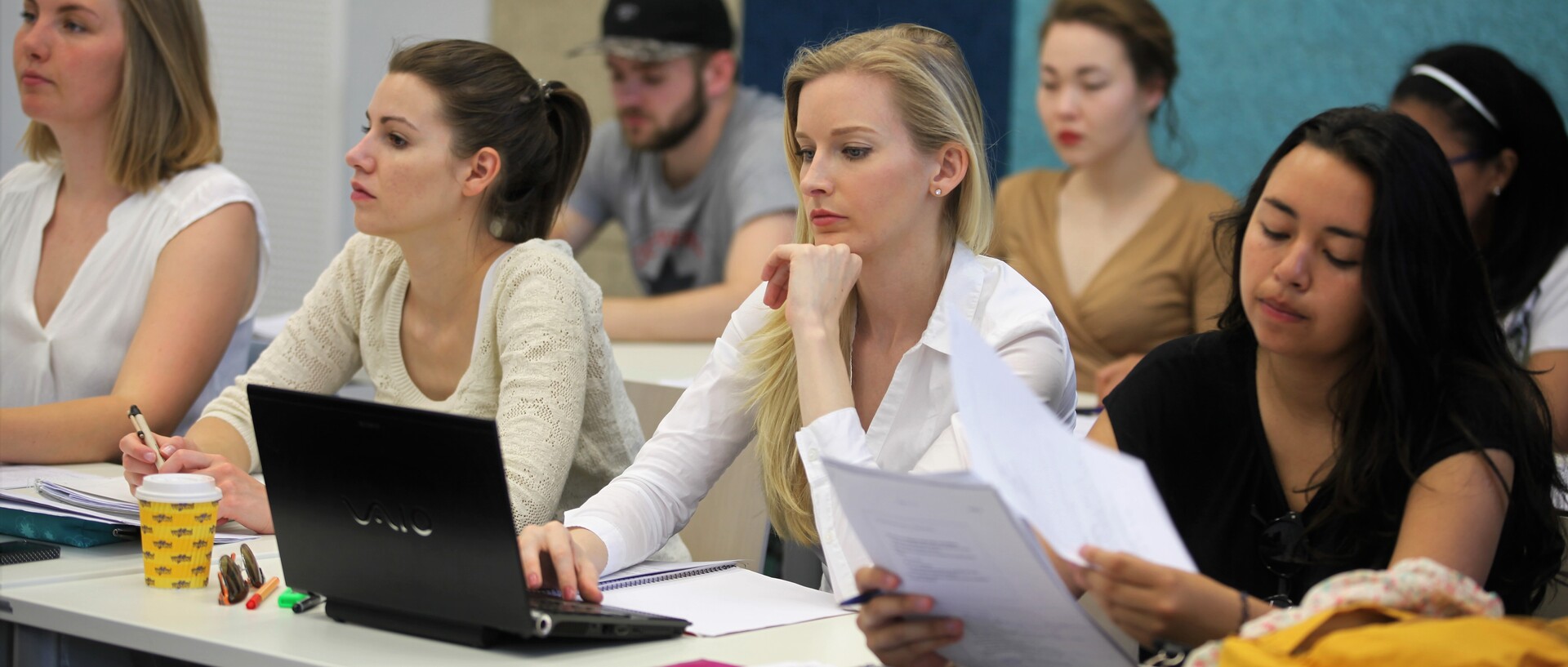 Studierende in Seminarraum hören zu.