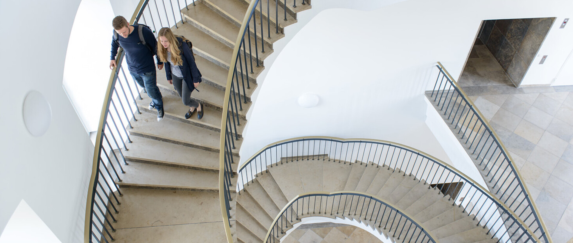 Zwei Menschen laufen Wendeltreppe hinunter