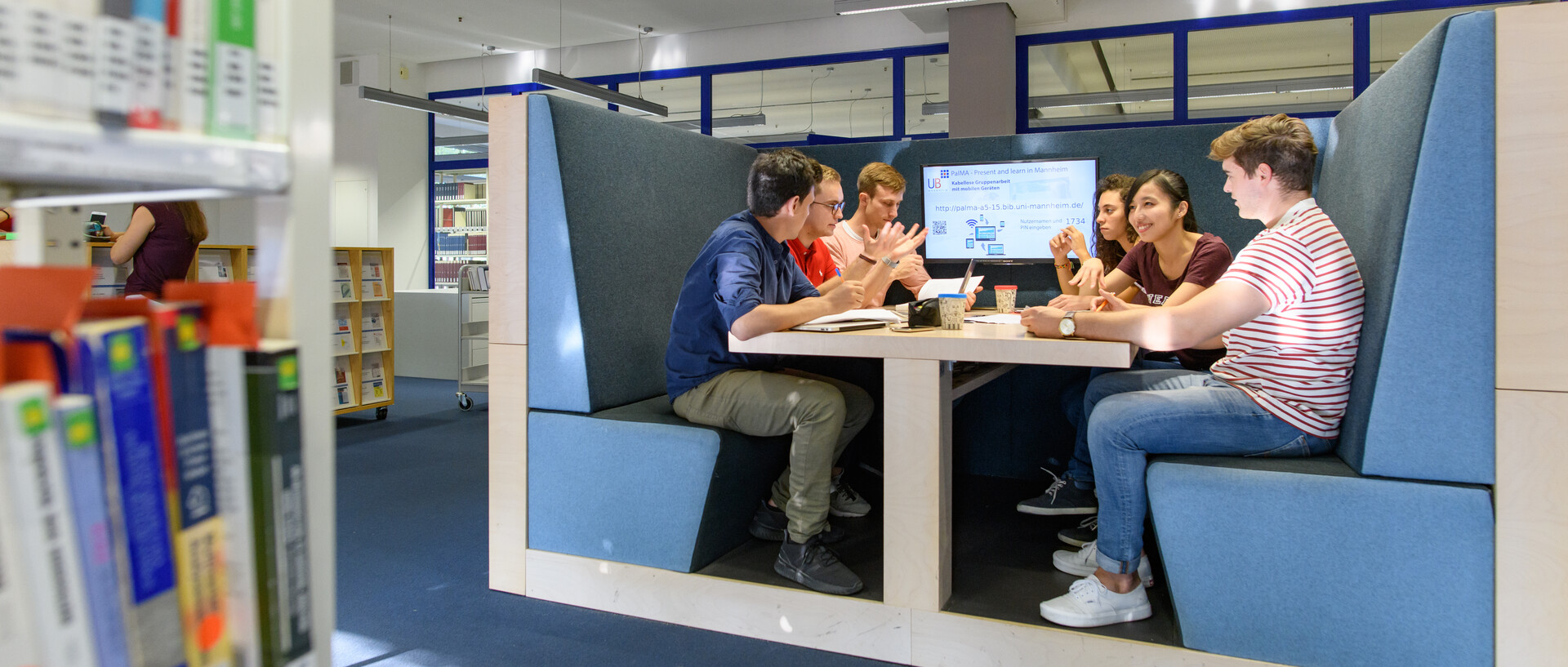 eine Gruppe Studierender sitzt an einem Gruppenarbeitsplatz in der Bibliothek