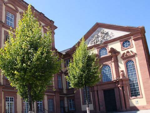Universitätskirche mit grünen Bäumen im Sonnenschein