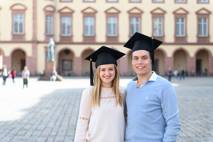 Zwei Studierende mit Hüten vor dem Schloss