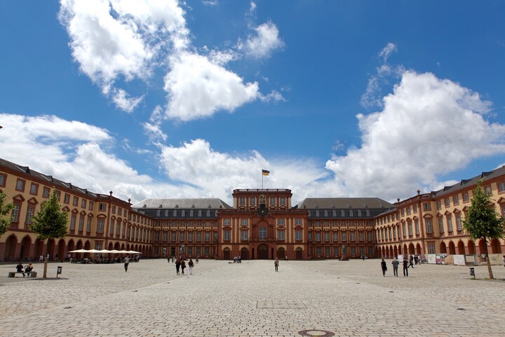 Ehrenhof und Schloss in der Sonne, weiße Wolken am blauen Himmel