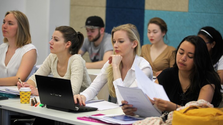 Studierende in Seminarraum hören zu.